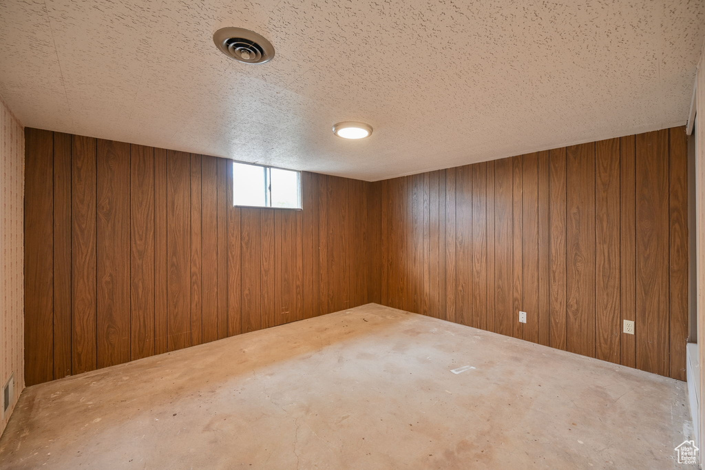 Basement with a textured ceiling and wooden walls