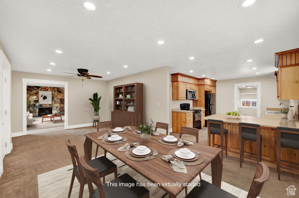 Dining area featuring a textured ceiling, light carpet, ceiling fan, and sink