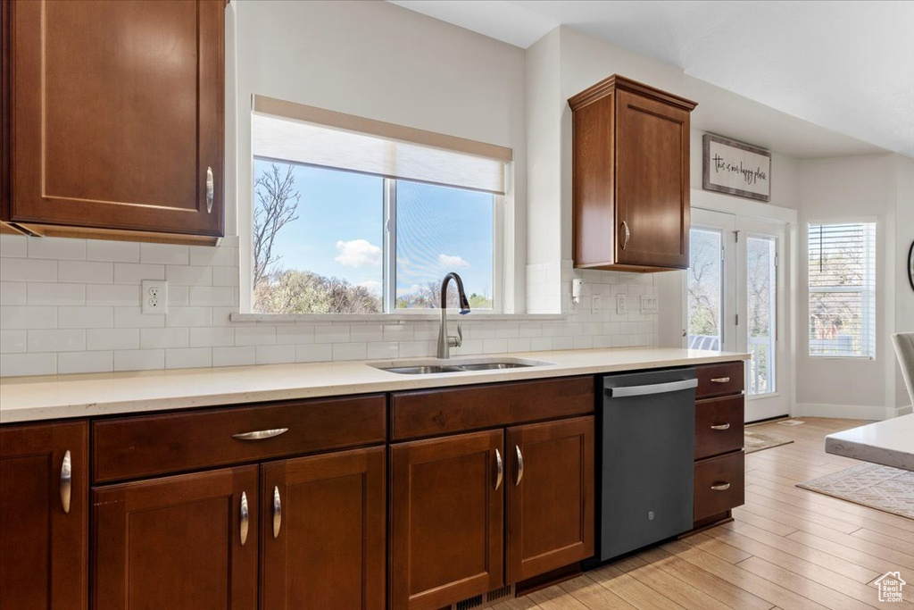 Kitchen featuring sink, light hardwood / wood-style flooring, tasteful backsplash, a wealth of natural light, and stainless steel dishwasher