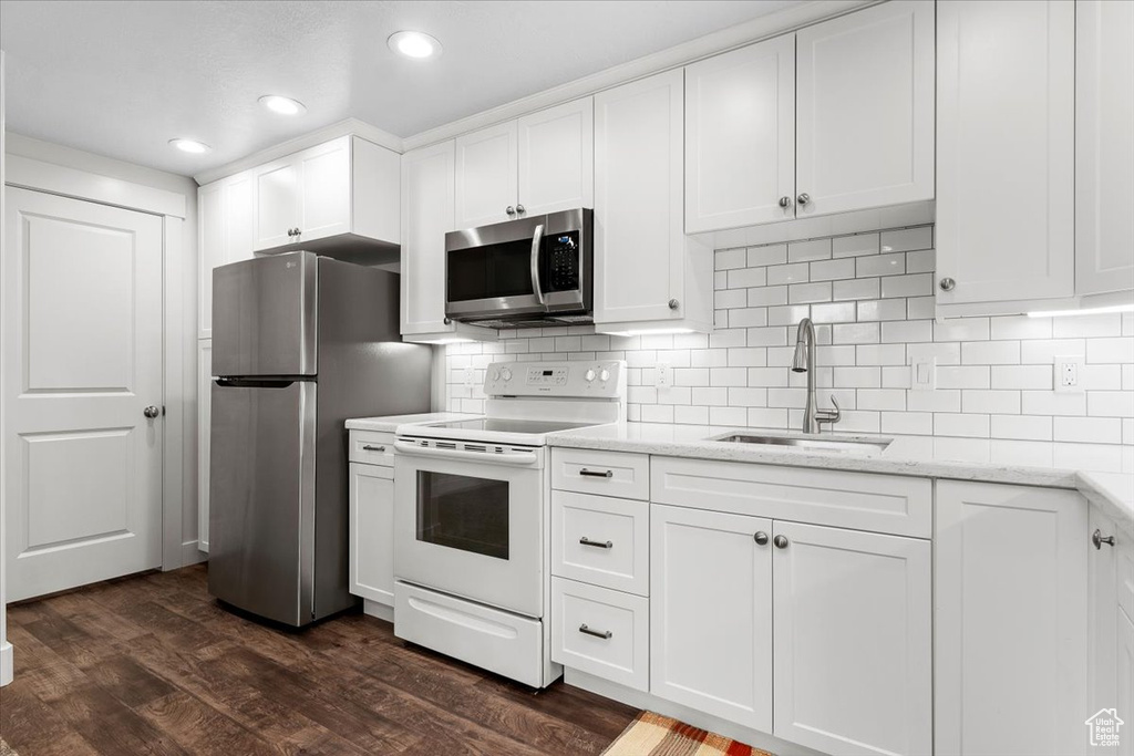 Kitchen featuring appliances with stainless steel finishes, dark hardwood / wood-style floors, sink, and white cabinets