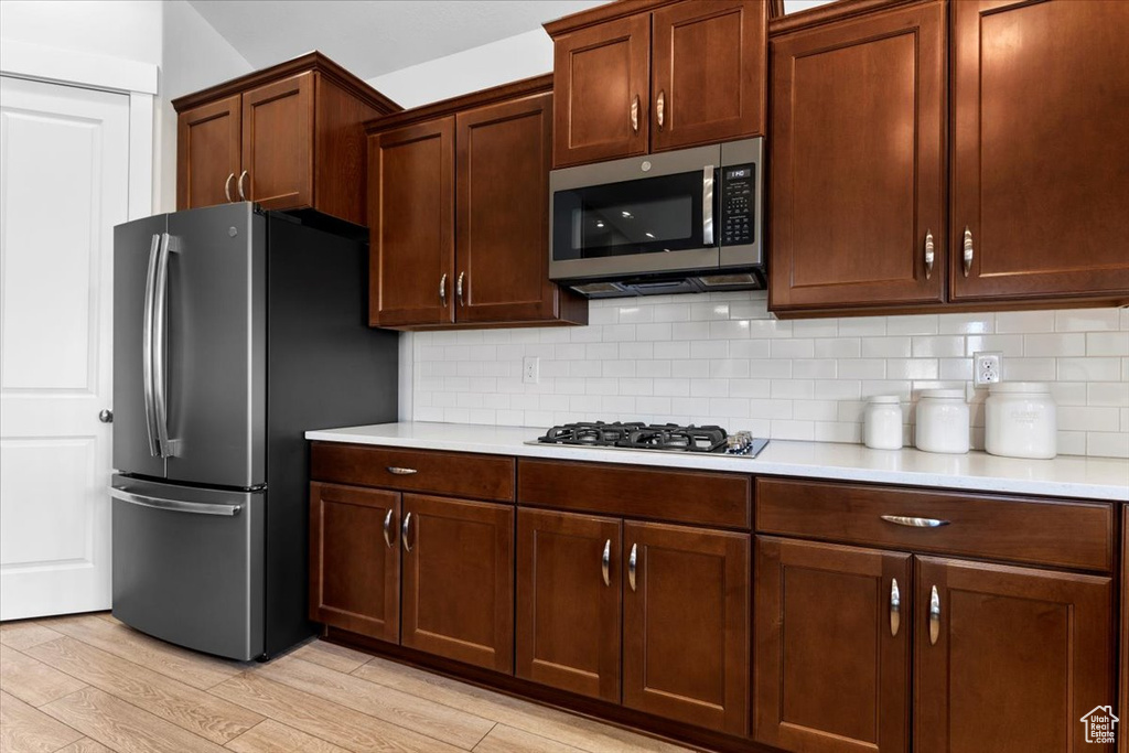 Kitchen featuring backsplash, light hardwood / wood-style floors, and stainless steel appliances