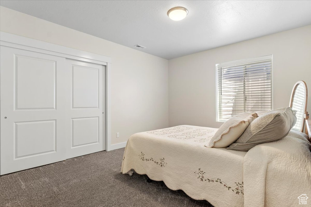 Bedroom with dark colored carpet and a closet