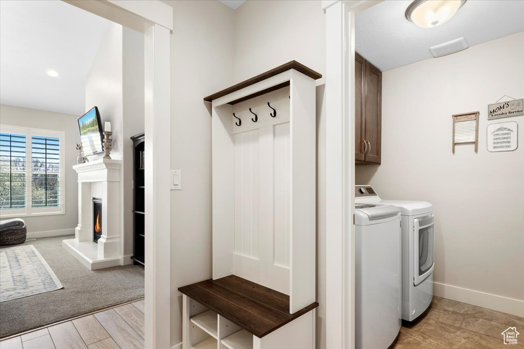 Washroom featuring light colored carpet, cabinets, and washing machine and clothes dryer