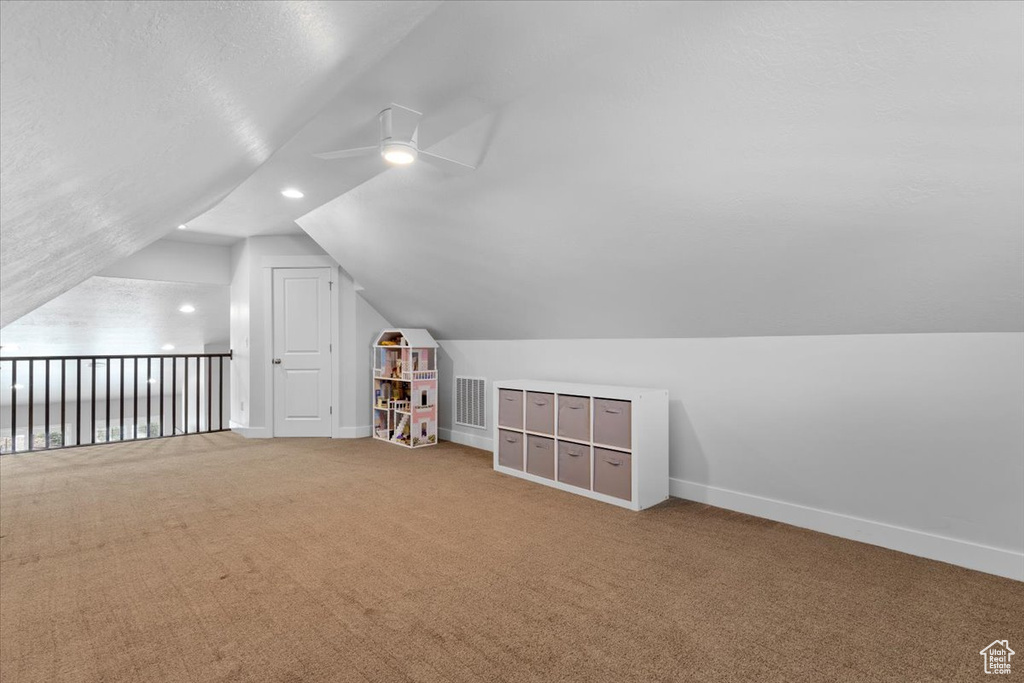 Bonus room with lofted ceiling, ceiling fan, and light carpet