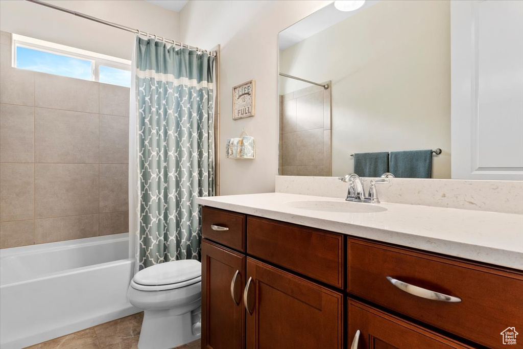 Full bathroom featuring large vanity, shower / bath combo, tile floors, and toilet