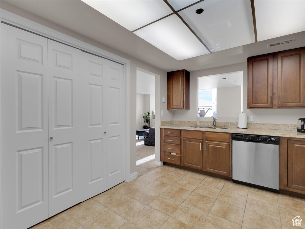 Kitchen featuring stainless steel dishwasher, sink, light carpet, and light stone countertops