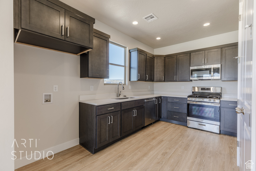 Kitchen featuring light hardwood / wood-style floors, stainless steel appliances, dark brown cabinetry, and sink