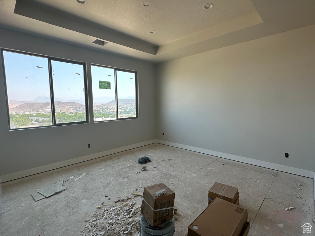 Unfurnished room with a raised ceiling and a textured ceiling