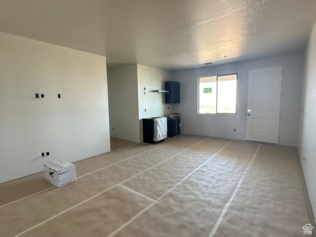 Unfurnished living room with concrete floors and a textured ceiling