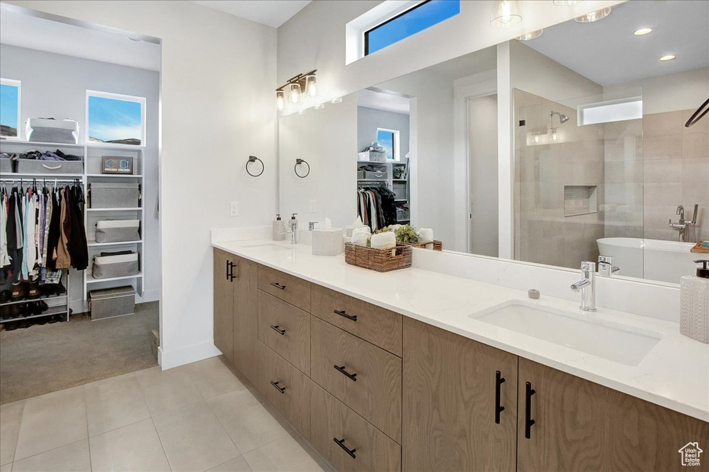 Bathroom featuring plenty of natural light, tile floors, tiled shower, and dual vanity