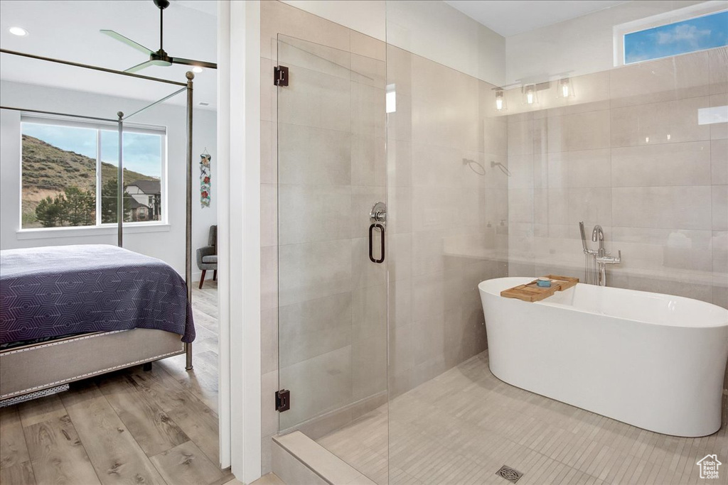 Bathroom featuring ceiling fan, tile walls, hardwood / wood-style flooring, and plus walk in shower