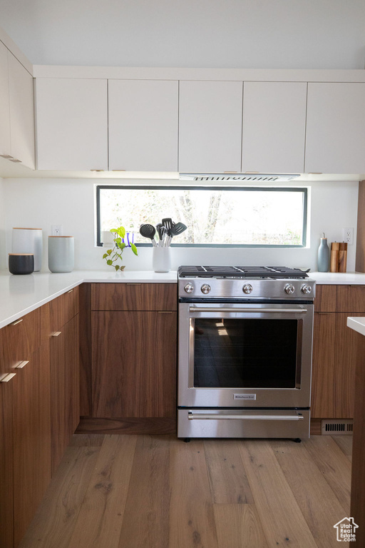 Kitchen with stainless steel stove, wood-type flooring, and white cabinets