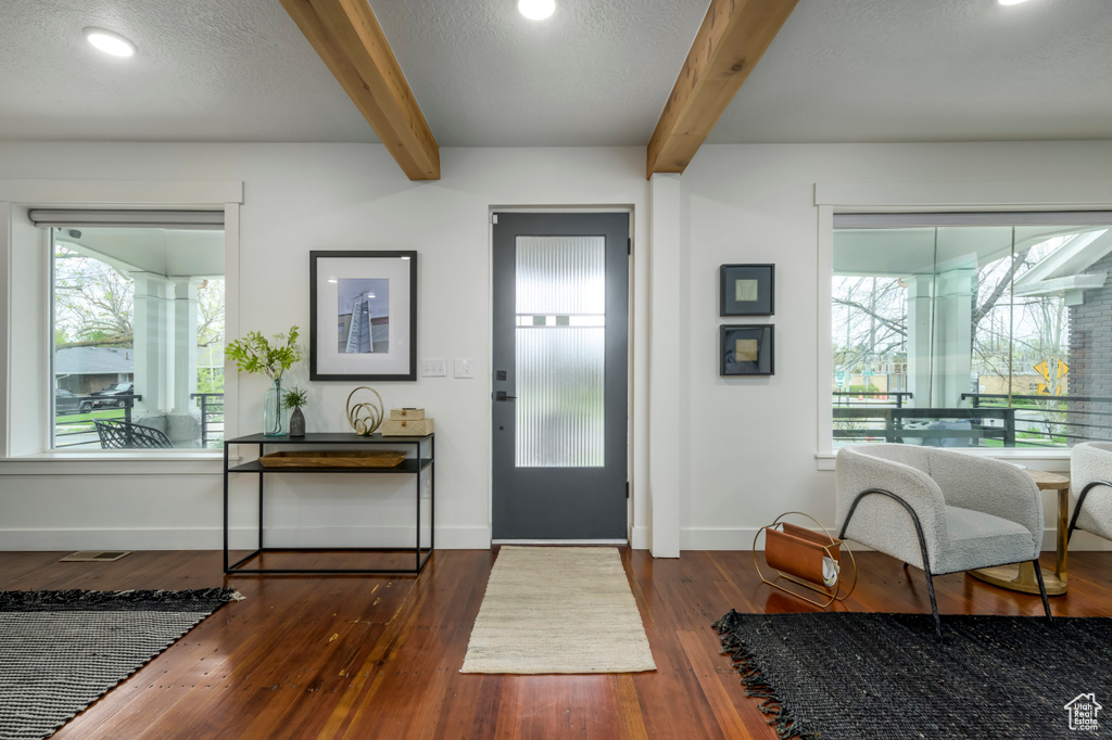 Foyer featuring beamed ceiling, dark hardwood / wood-style floors, and a textured ceiling