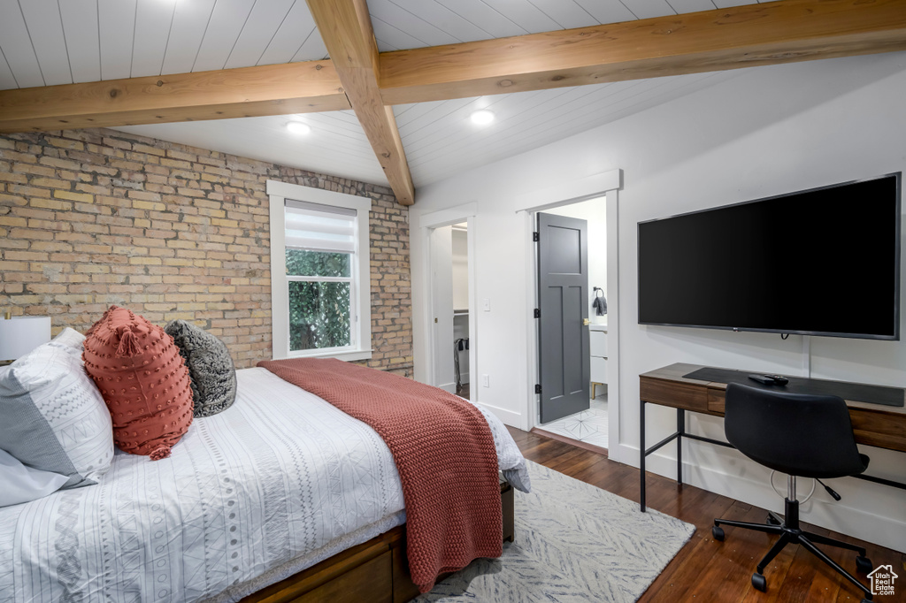 Bedroom with brick wall, dark hardwood / wood-style flooring, and beam ceiling
