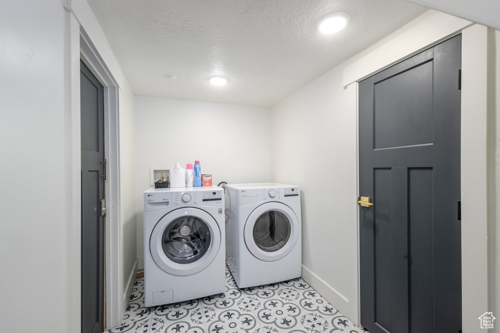 Washroom featuring independent washer and dryer, hookup for a washing machine, a textured ceiling, and light tile flooring
