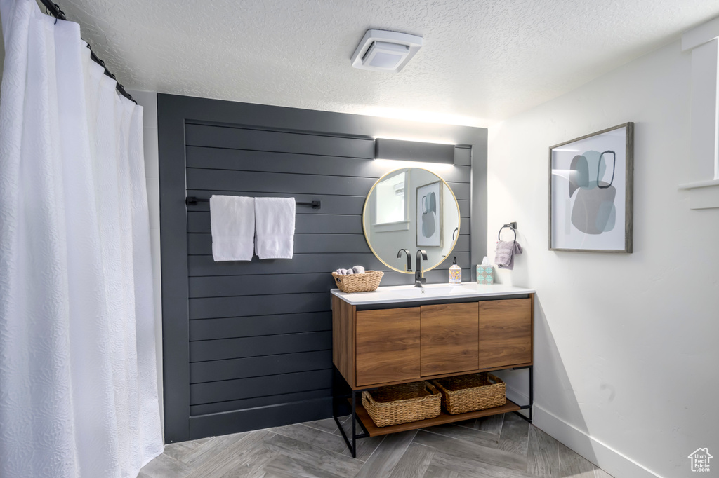 Bathroom featuring vanity with extensive cabinet space, a textured ceiling, and parquet floors