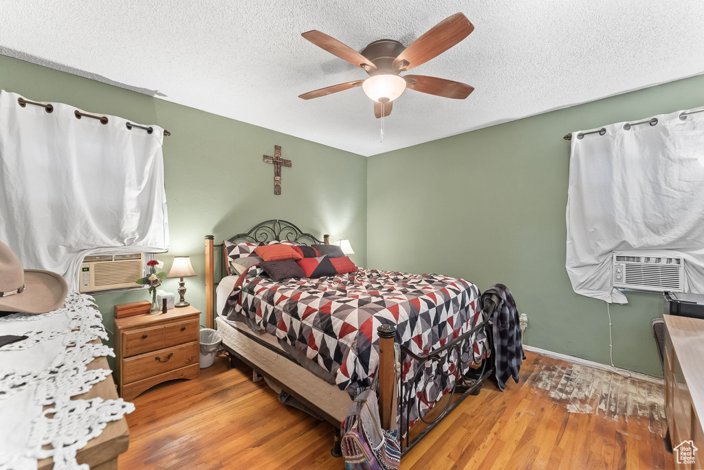Bedroom featuring light hardwood / wood-style flooring, ceiling fan, and a textured ceiling