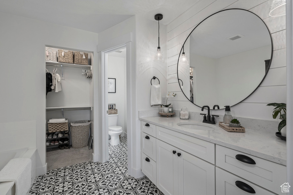 Bathroom featuring tile flooring, vanity, toilet, and a washtub