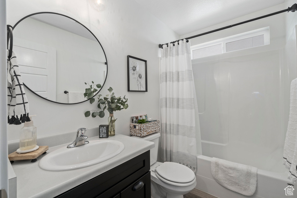Full bathroom with vanity with extensive cabinet space, shower / tub combo, and toilet
