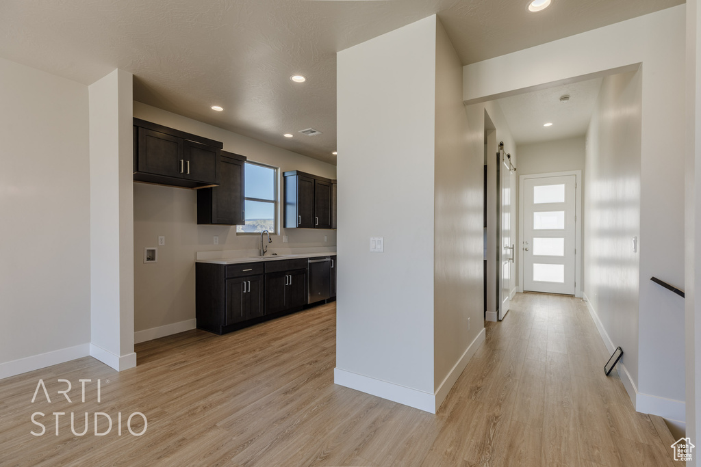 Kitchen with stainless steel dishwasher, sink, and light hardwood / wood-style floors