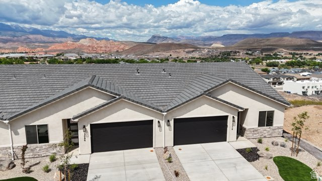 Ranch-style house featuring concrete driveway, a garage, a mountain view, and stucco siding