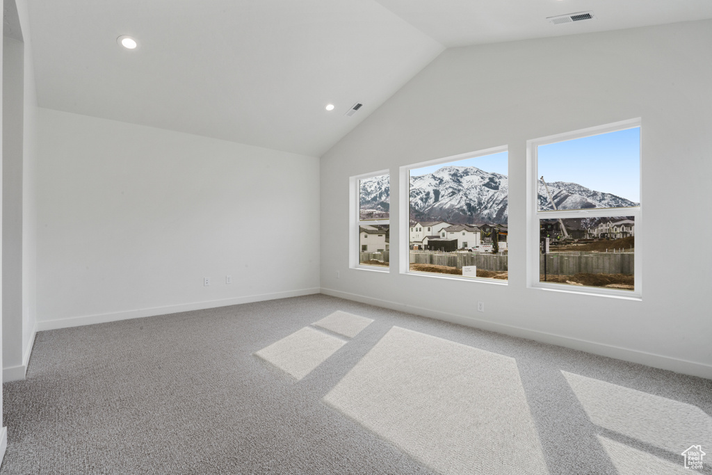 Carpeted empty room with a mountain view and lofted ceiling