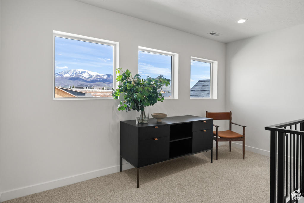Interior space with a wealth of natural light, light carpet, and a mountain view