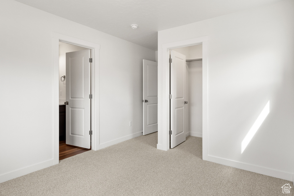 Unfurnished bedroom featuring light colored carpet, a closet, and a spacious closet