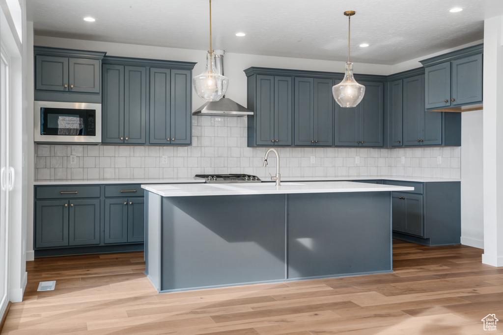 Kitchen featuring tasteful backsplash, black microwave, pendant lighting, and hardwood / wood-style flooring