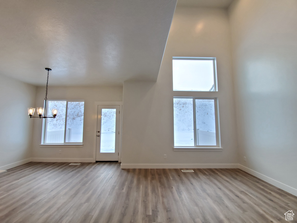 Empty room with hardwood / wood-style flooring and a notable chandelier