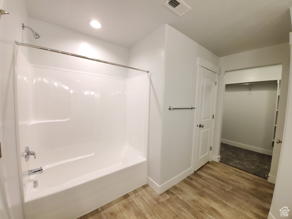 Bathroom with shower / bathing tub combination and hardwood / wood-style flooring