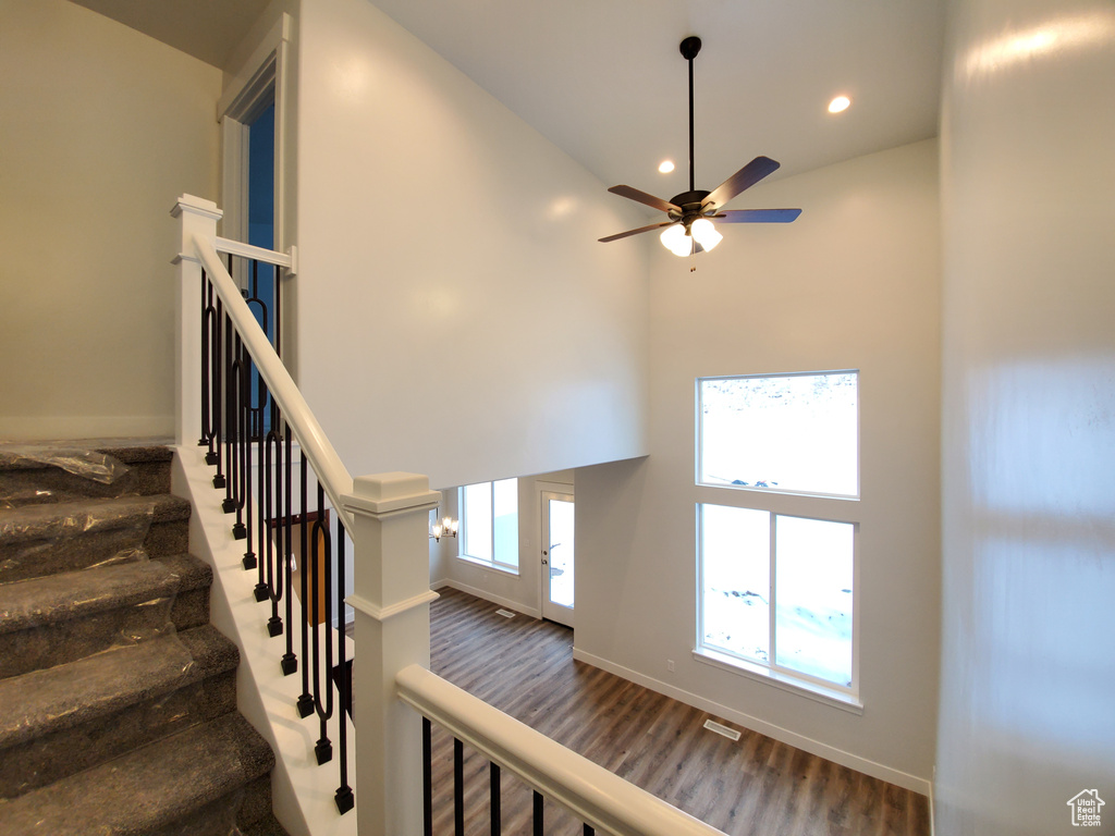 Stairway featuring high vaulted ceiling, dark hardwood / wood-style flooring, and ceiling fan