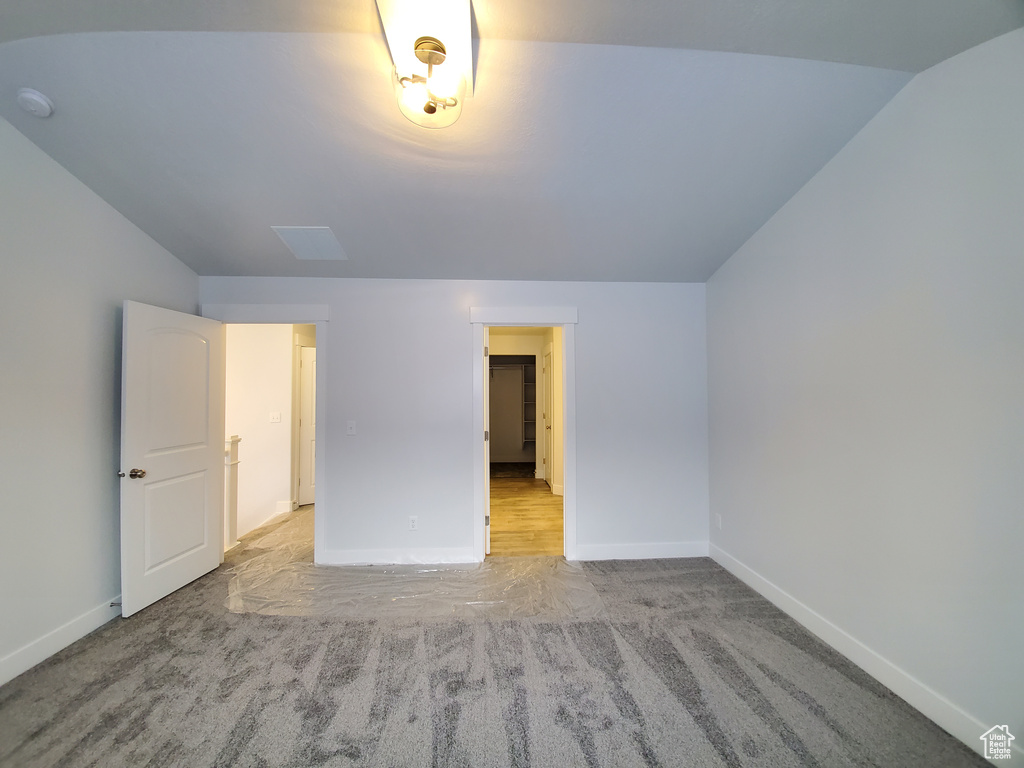 Unfurnished bedroom with light carpet and lofted ceiling