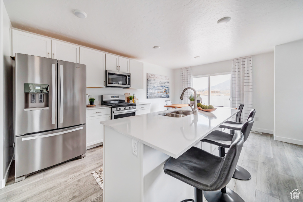Kitchen featuring white cabinets, light hardwood / wood-style flooring, sink, and stainless steel appliances