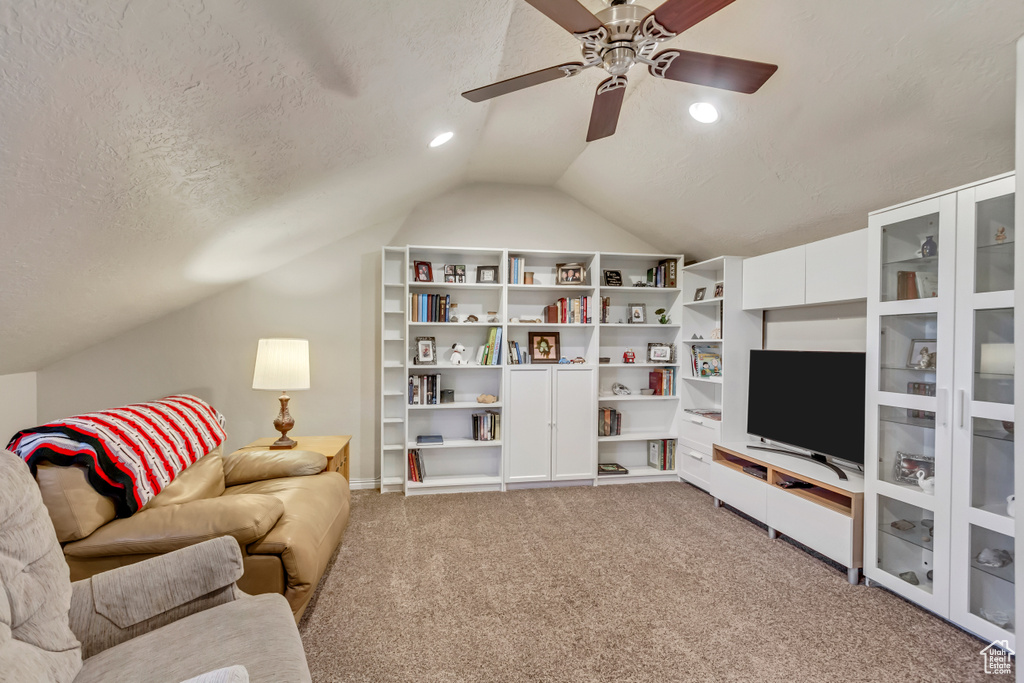 Living room with vaulted ceiling, ceiling fan, carpet, and a textured ceiling
