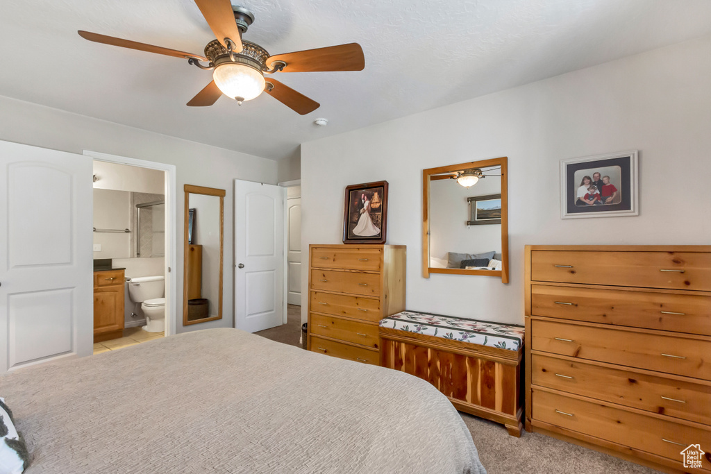 Carpeted bedroom with ceiling fan and connected bathroom