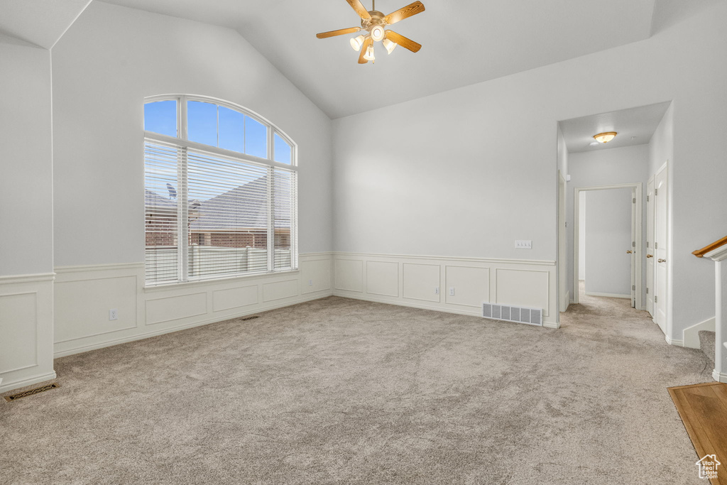 Carpeted empty room with ceiling fan and vaulted ceiling