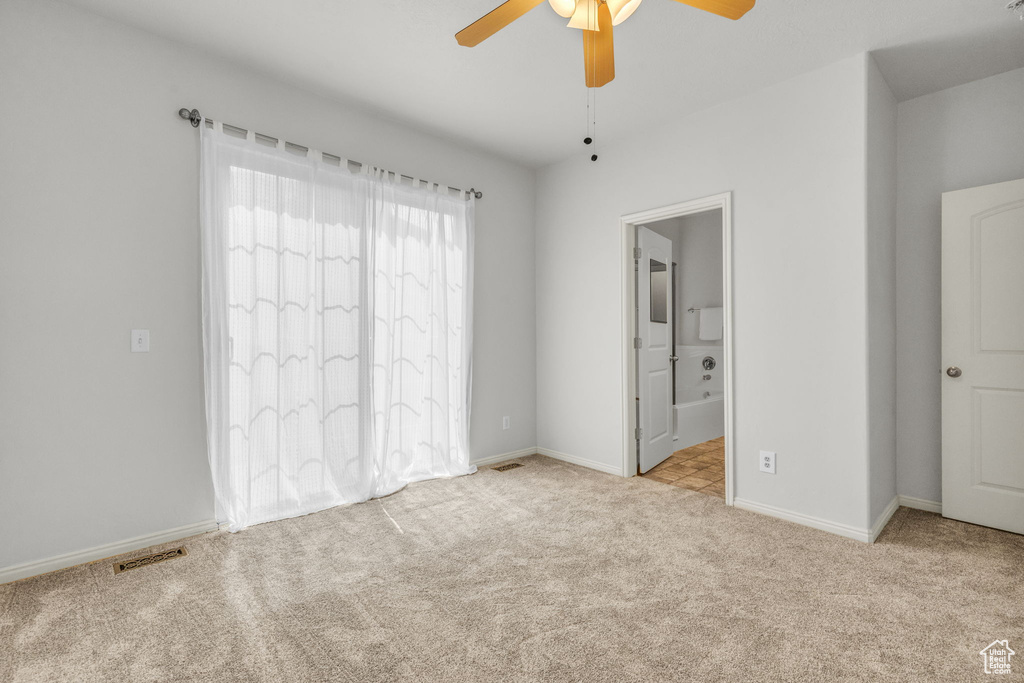 Unfurnished bedroom featuring ensuite bath, ceiling fan, and light carpet