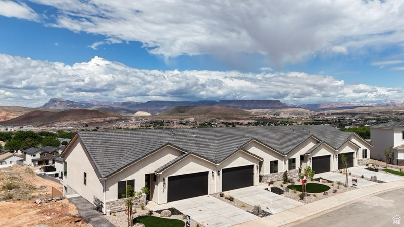 Ranch-style house with driveway, a garage, stucco siding, and a mountain view