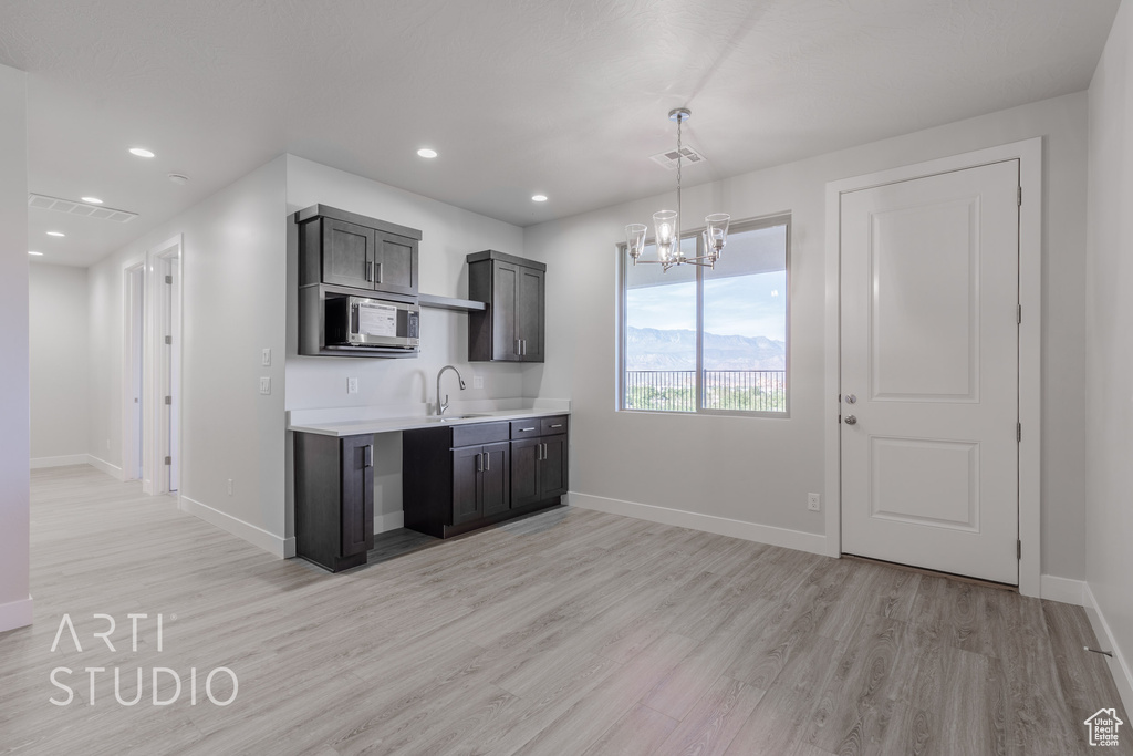 Kitchen featuring an inviting chandelier, sink, decorative light fixtures, and light wood-type flooring