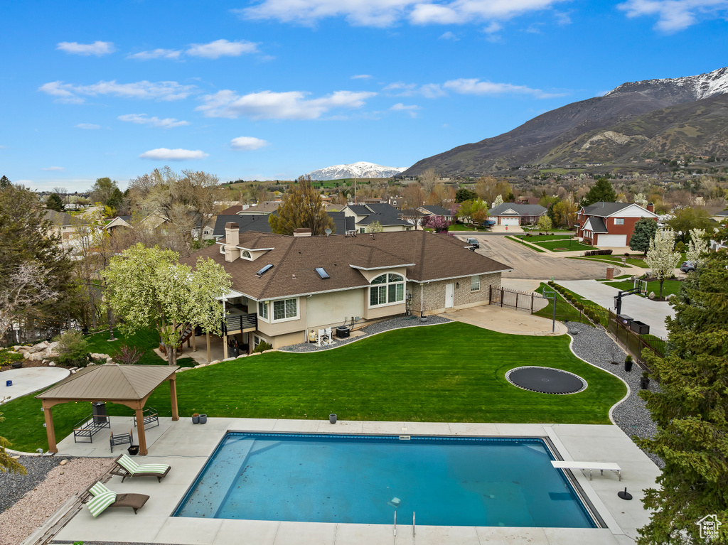 View of swimming pool featuring a mountain view, a diving board, a yard, and a patio area