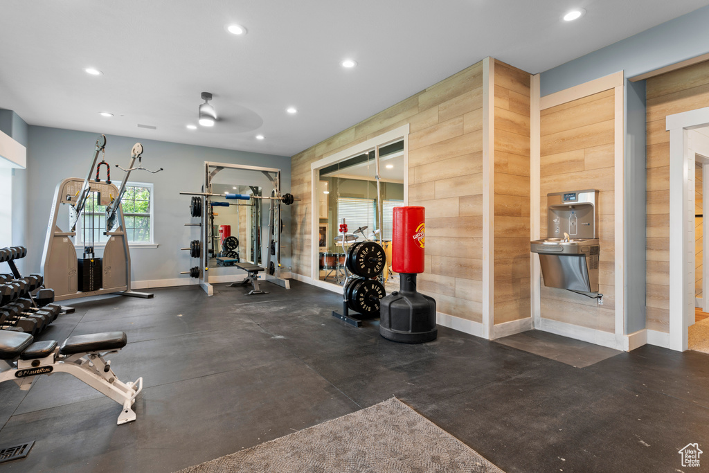 Exercise room featuring wood walls and ceiling fan