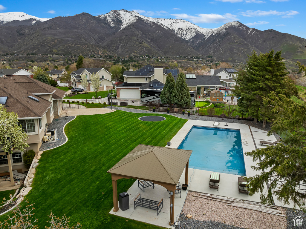 View of swimming pool with a patio area, a mountain view, and a lawn