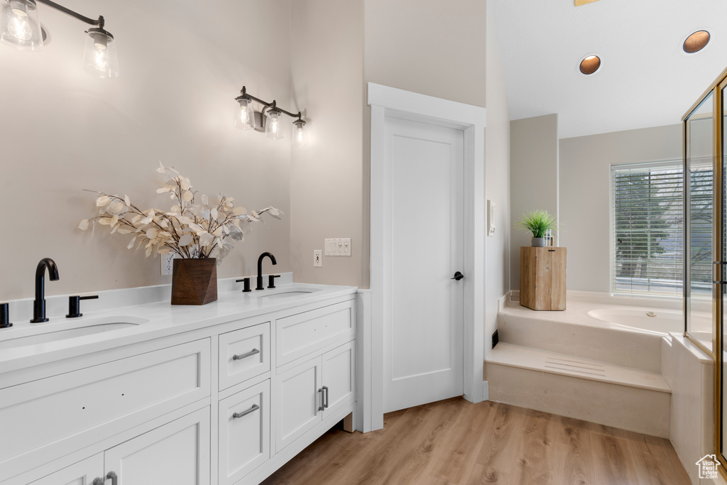 Bathroom featuring wood-type flooring, dual vanity, and a bathtub