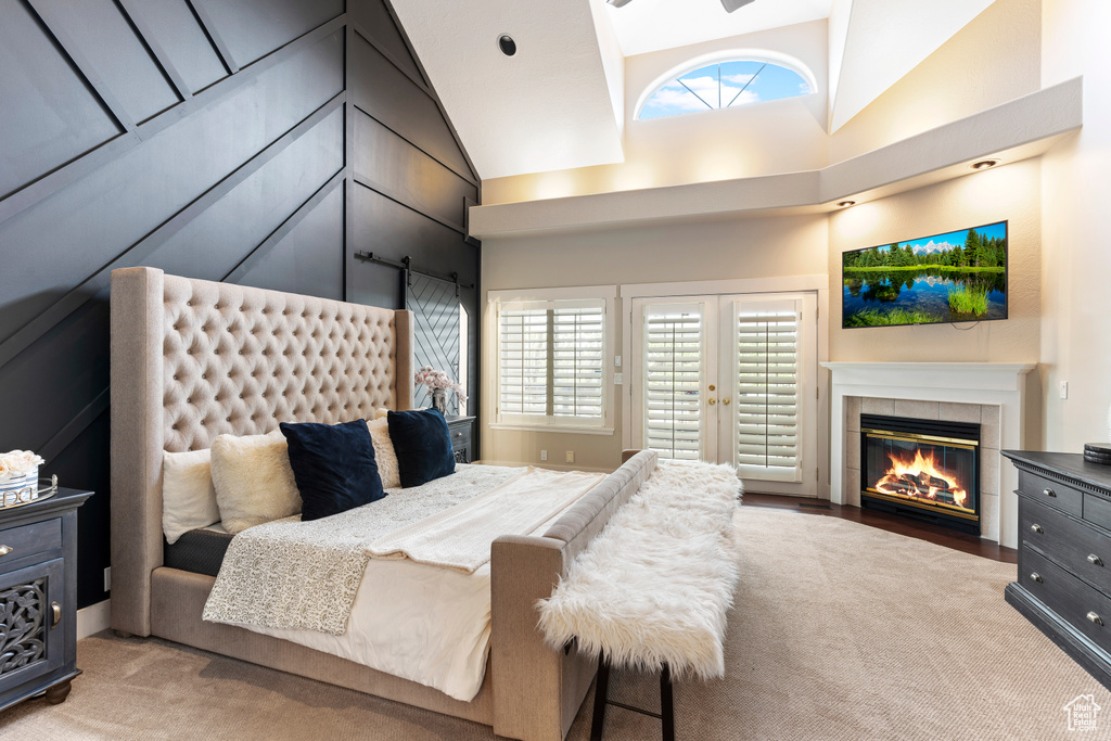 Bedroom featuring high vaulted ceiling, french doors, light hardwood / wood-style floors, access to exterior, and a fireplace