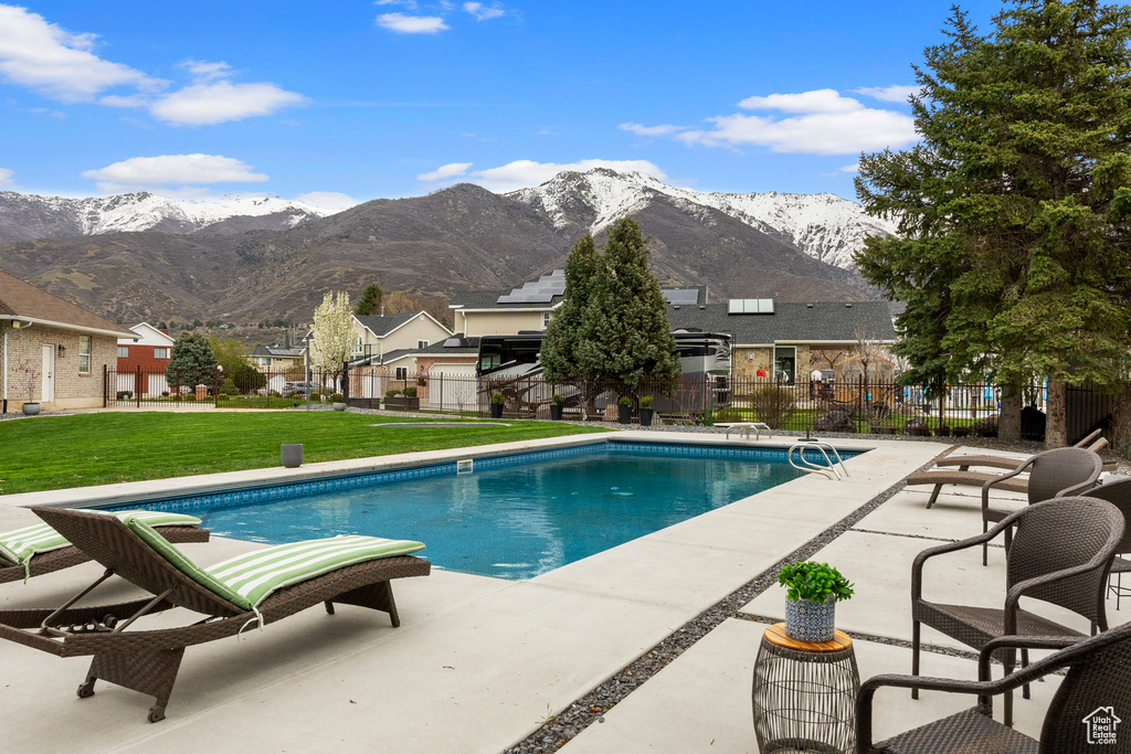 View of swimming pool featuring a patio, a mountain view, and a yard