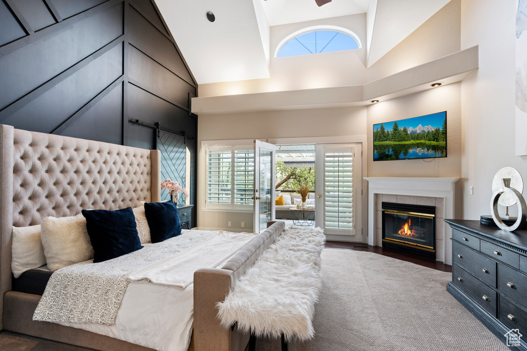 Bedroom with high vaulted ceiling, dark hardwood / wood-style floors, and a tiled fireplace