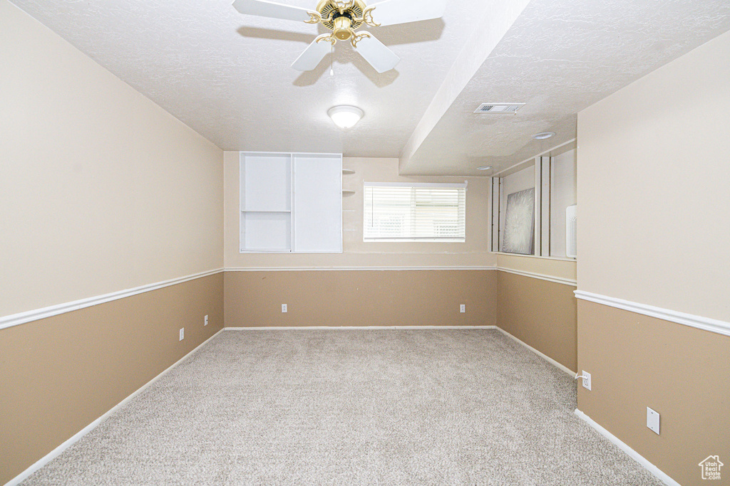 Carpeted empty room featuring ceiling fan and a textured ceiling