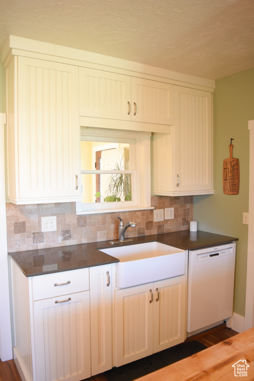 Kitchen featuring sink, dark hardwood / wood-style flooring, backsplash, and white dishwasher
