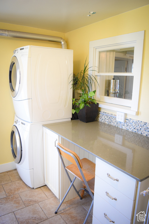 Laundry room featuring stacked washer / dryer and light tile flooring